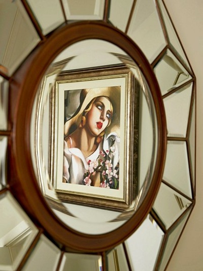 Tamara de Lempika artwork seen through a faceted mirror in bedroom interior